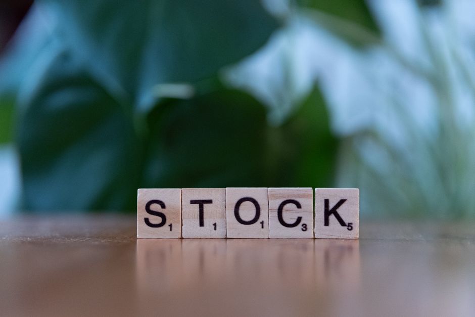 Episode 2: The Expiring Batch Nightmare Close-up of wooden letter blocks spelling 'STOCK' on a table against a blurred green background.