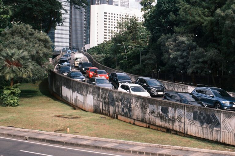 Heavy traffic on a Jakarta overpass surrounded by greenery and skyscrapers.