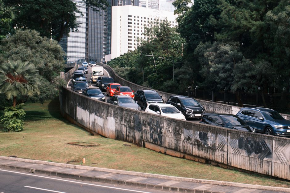 Episode 1: The 4:30 PM Friday Traffic Crisis Heavy traffic on a Jakarta overpass surrounded by greenery and skyscrapers.
