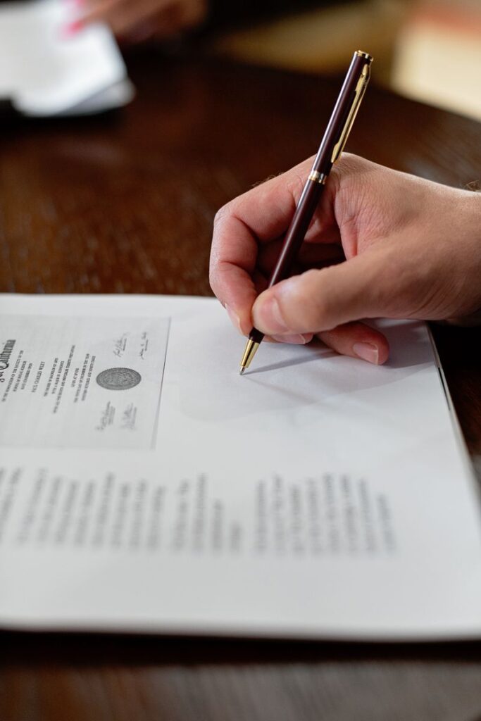 Episode 7: The Unannounced 10:00 AM Audit A detailed close-up photo of a hand signing a formal document with a pen, creating a professional agreement.
