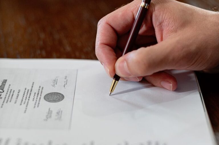 A detailed close-up photo of a hand signing a formal document with a pen, creating a professional agreement.
